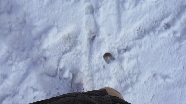 冬天，穿着白色运动鞋的男人在雪地里慢镜头行走视频素材