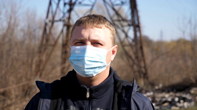 新冠肺炎疫情期间，佩戴医用口罩的男子站在城市街道上。戴着防护口罩的人。应对冠状病毒大流行的健康和安全生命理念。视频素材