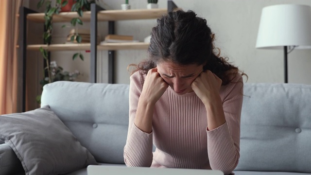 忧心忡忡的女人看着笔记本电脑，感觉沮丧的阅读坏消息视频素材