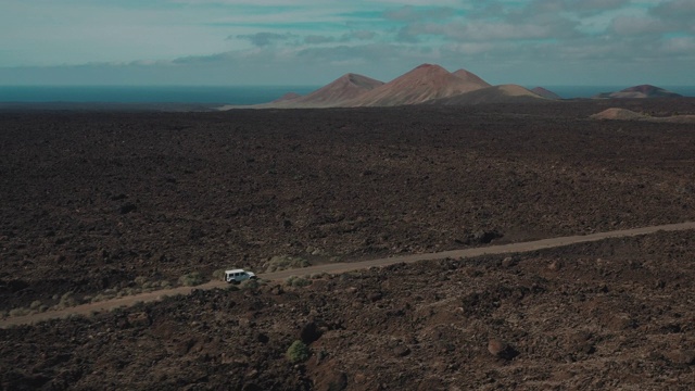 空中跟踪拍摄显示了一辆4x4汽车在一个火山景观，兰萨罗特，西班牙视频素材