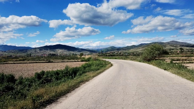 汽车在农地之间的乡间柏油路上行驶视频素材