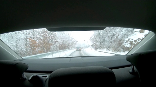 穿过后挡风玻璃——在暴风雪中行驶在覆盖着积雪的山路上视频素材