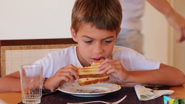 孩子吃三明治英俊的小男孩咬了一口他的火腿和奶酪三明治视频素材