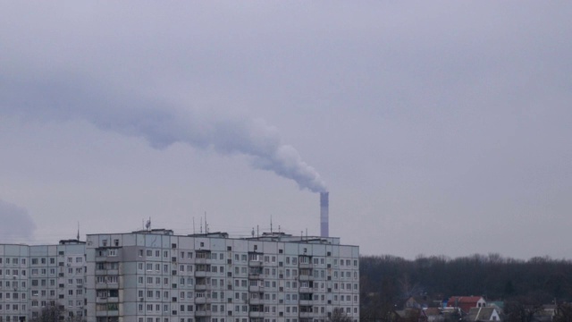 从多层住宅附近的烟囱排放二氧化碳的热电厂。浓烟从烟囱里排入大气。环境污染的概念。视频素材