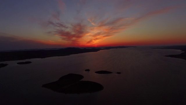 空中平移拍摄的日落在海上和岛屿对橙色的天空，无人机飞过美丽的自然景观-心岛，克罗地亚视频素材