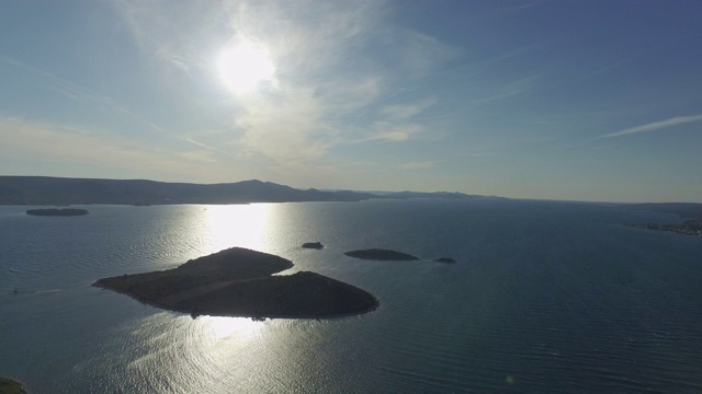 空中平移拍摄的心形岛在海洋对蓝色的天空，无人机在阳光明媚的一天附近的山在海上飞行-心岛，克罗地亚视频素材