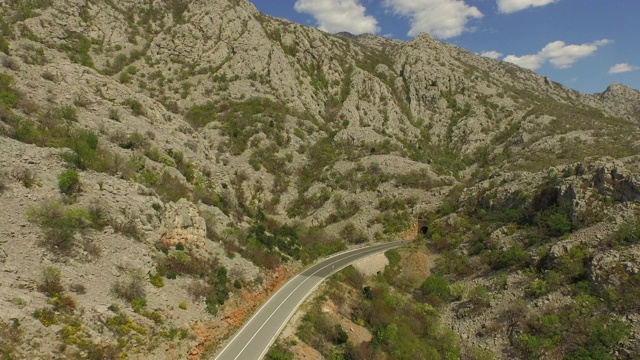 空中拍摄的汽车在高速公路上的岩石山对天空，无人机上升的道路上晴天-帕格，克罗地亚视频素材