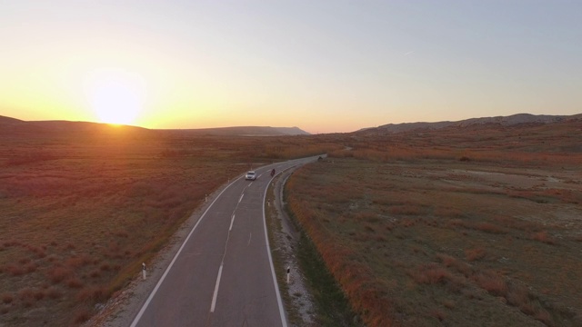 从空中拍摄的人们在高速公路上骑车，日落时分，无人机在植物中间向后飞行的道路上——拉扎纳克，克罗地亚视频素材