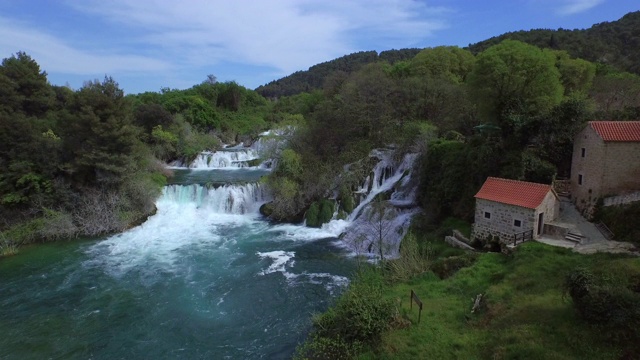 空中拍摄的美丽的瀑布中树木对天空，无人机飞向瀑布的建筑- Krka，克罗地亚视频素材