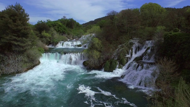 空中拍摄的瀑布在森林中的树木对天空，无人机飞向美丽的瀑布- Krka，克罗地亚视频素材