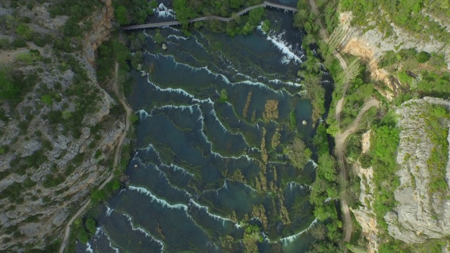 航拍河流在山谷的岩石山中流动，无人机在森林中的绿色植物中飞过水- Krka，克罗地亚视频素材