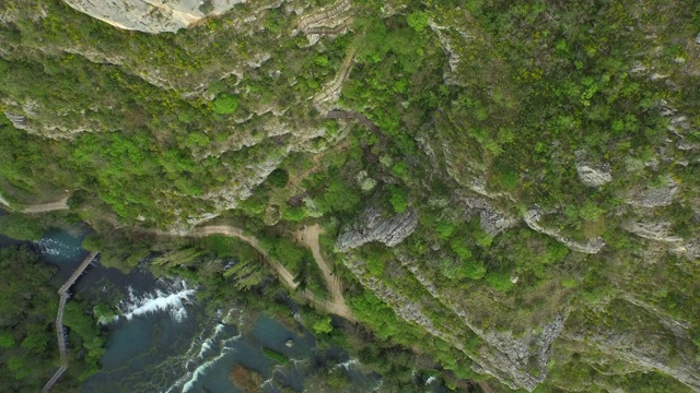 航拍的岩石山与绿色植物的河流在森林里，无人机飞过水流动的山谷-克尔卡，克罗地亚视频素材