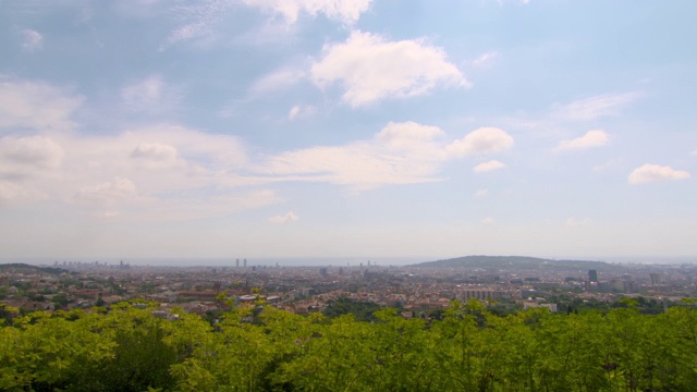 晴朗的一天，空中封锁拍摄的树木，以天空为背景的城市——西班牙巴塞罗那视频素材