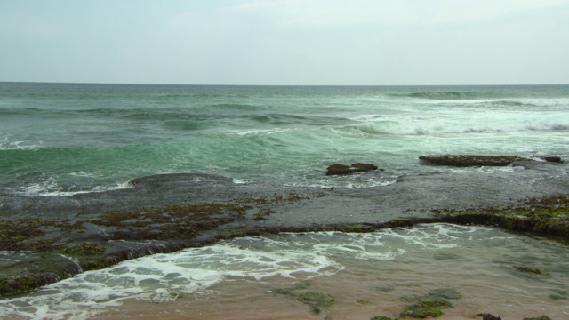 斯里兰卡阿鲁甘湾，天空下的海浪拍打着海滩上的岩石视频素材