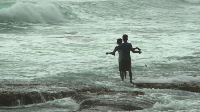 年轻男子在海滩上钓鱼-阿鲁甘湾，斯里兰卡，海浪溅起的镜头视频素材