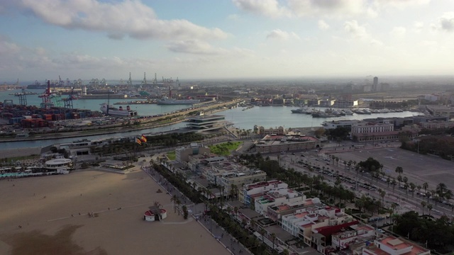 航拍港口附近的海滩建筑对天空，无人机在城市景观在日落-瓦伦西亚，西班牙视频素材