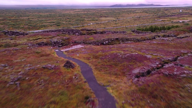 空中拍摄的溪流流过绿色的风景，无人机飞向汽车在高速公路上- Oxararfoss，冰岛视频素材