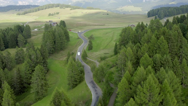 航拍公路上绿树环绕的巴士，无人机在风景上空飞行——意大利Dolomites视频素材