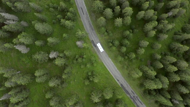 意大利Dolomites公路上绿树成荫的巴士鸟瞰图，无人机在车辆上空飞行视频素材