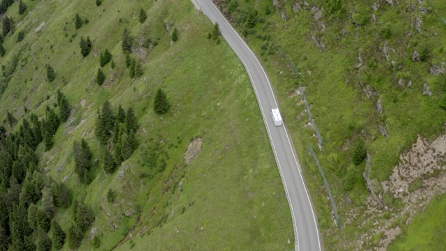 空中拍摄的巴士在高速公路上越过绿色的山，无人机飞过在山区公路上的车辆- Dolomites，意大利视频素材