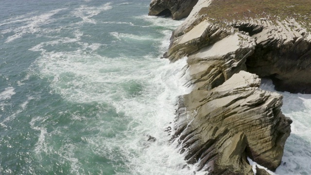 航拍海浪拍打在岩石形成的海洋，无人机飞向岩石悬崖在阳光明媚的一天-阿尔加维，葡萄牙视频素材