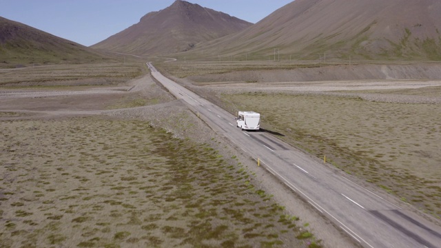 航拍的大篷车在向山脉的道路上移动，无人机向前飞行在风景中的车辆-冰岛西南部，冰岛视频素材