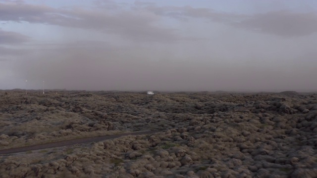 航拍:在大雾天气中，露营车在岩层中行驶，日落时无人机在岩石景观上飞行。冰岛西南部视频素材