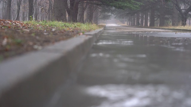 落寞的秋雨后巷，流水淹没了沥青路。视频素材