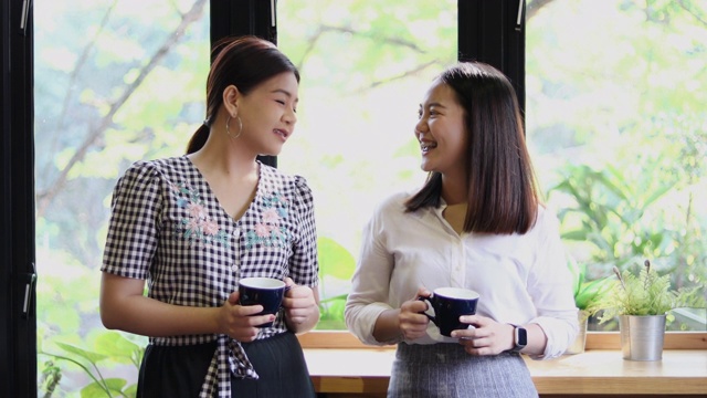 两个亚洲女人喝咖啡和愉快的女人闲谈在咖啡馆视频素材