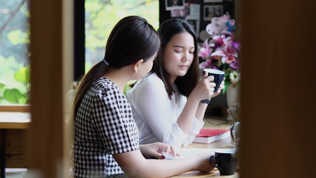 两个亚洲女人喝咖啡和愉快的女人闲谈在咖啡馆视频素材