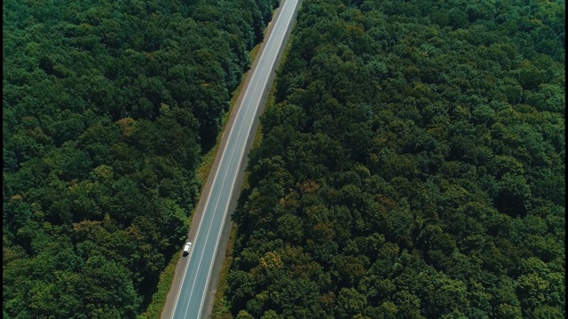 空中拍摄的视频显示，汽车沿着蜿蜒的道路穿过绿树成荫的森林。视频素材