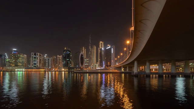 日以继夜，湖面、河流和桥在迪拜市中心天际线，阿拉伯联合酋长国或阿联酋。城市中的金融区。晚上的摩天大楼。视频素材