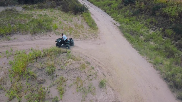 在乡村公路上驾驶Quad汽车的人。穿着休闲的男人骑着一辆黑色四轮车。视频下载