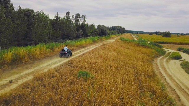 在乡村公路上驾驶Quad汽车的人。穿着休闲的男人骑着一辆黑色四轮车。视频下载