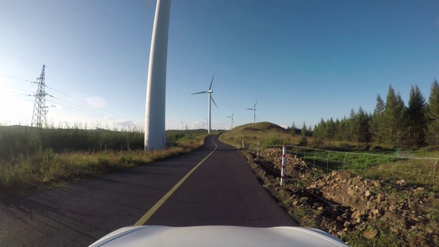 4K交通鸟瞰图白色汽车行驶在蜿蜒的道路上向风力发电机视频素材