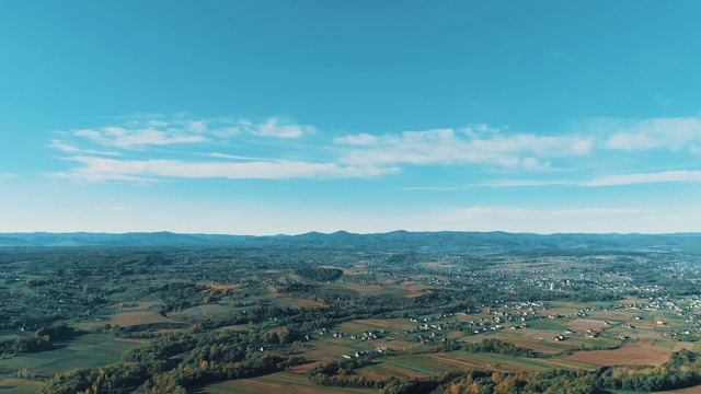 飞过秋日的山村，在柔和的阳光下，有森林和田野。视频素材