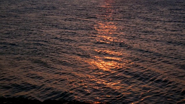 海浪在夕阳下发出光芒。海面上日出的倒影。慢动作视频素材