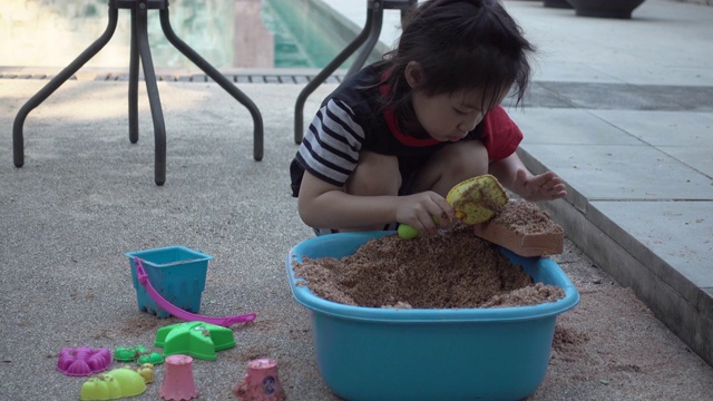 亚洲小女孩一起在院子里玩沙子玩得很开心。真实生活，手持拍摄视频下载