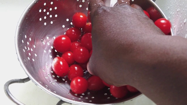 在白色水槽的钢制滤锅中清洗樱桃番茄视频下载