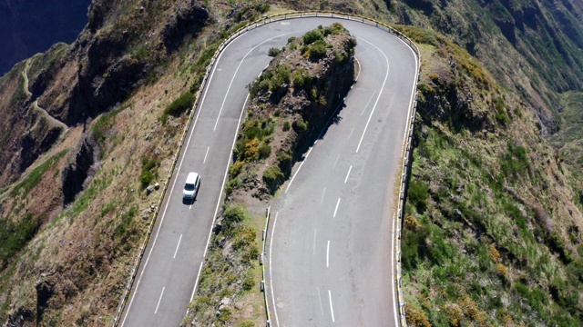 4K无人机从高处拍摄的画面:一辆汽车在蜿蜒的道路上通过弯道视频素材