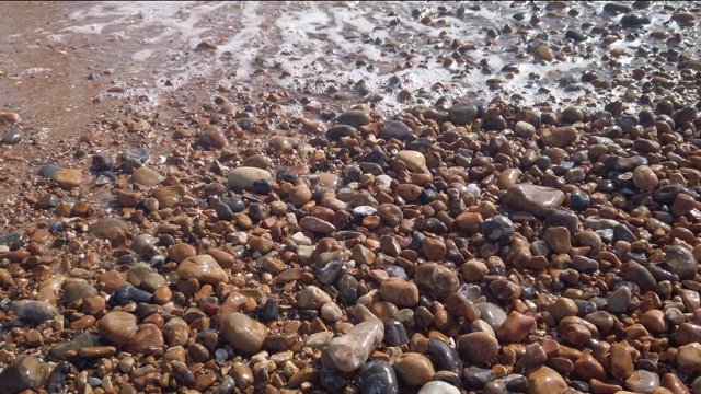 慢镜头放大在布莱顿海滩鹅卵石上的海浪，英国视频下载