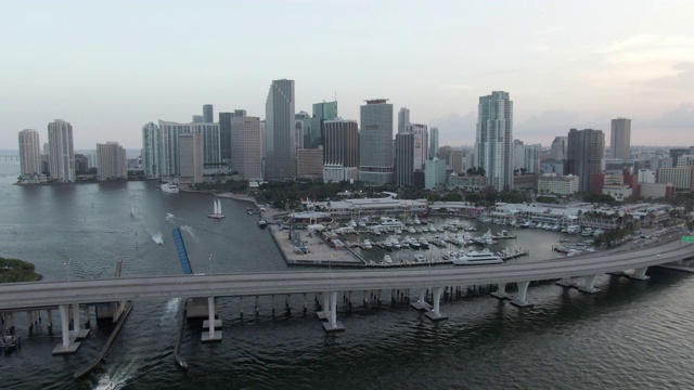 航拍的船只在海上的港口和建筑物对天空，无人机在城市大桥上向前飞行在日落-迈阿密，佛罗里达视频素材