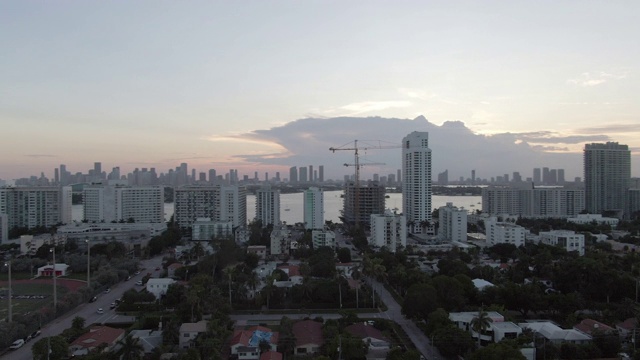 空中平移拍摄的车辆在街道上的建筑物对天空，无人机飞过城市在日落-迈阿密，佛罗里达视频素材