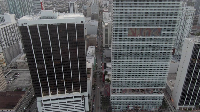 空中倾斜拍摄在城市摩天大楼之间的街道上的车辆，在日落时无人机在城市上空上升-迈阿密，佛罗里达视频素材