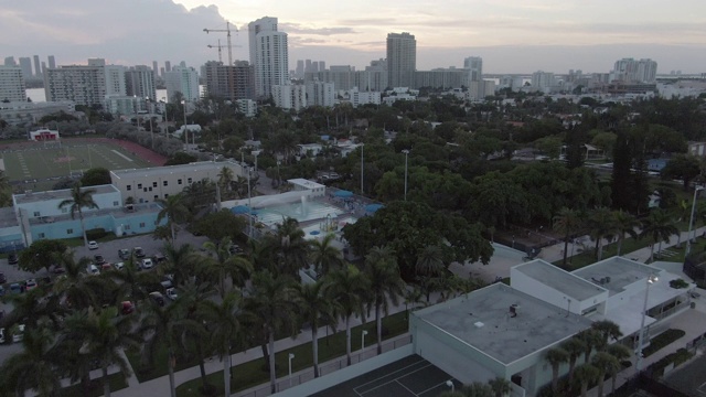 空中拍摄的人打网球在树对天空，无人机飞过城市在日落-迈阿密，佛罗里达视频素材