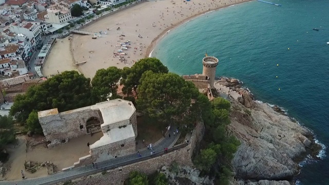 航拍游客在城市的海滩上著名的城堡，无人机向前飞行的海洋- Tossa de Mar，西班牙视频素材