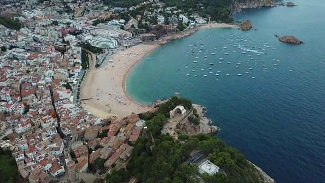 空中倾斜拍摄的沿海城市与地标和山脉，无人机在海上对着天空飞行- Tossa de Mar，西班牙视频素材