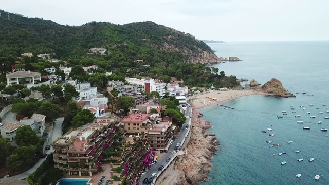 航拍的船只停泊在海上的城市与天空，无人机在海滩上向前飞行- Tossa de Mar，西班牙视频素材