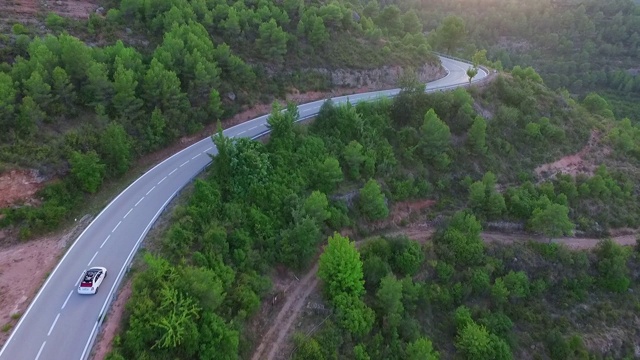 航拍在绿树和植物之间的道路上的汽车，无人机在日落期间在自然景观上方飞行-蒙特塞拉特，西班牙视频素材