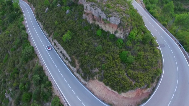 空中倾斜拍摄在绿树和植物之间的道路上的汽车，无人机飞过自然景观-蒙特塞拉特，西班牙视频素材